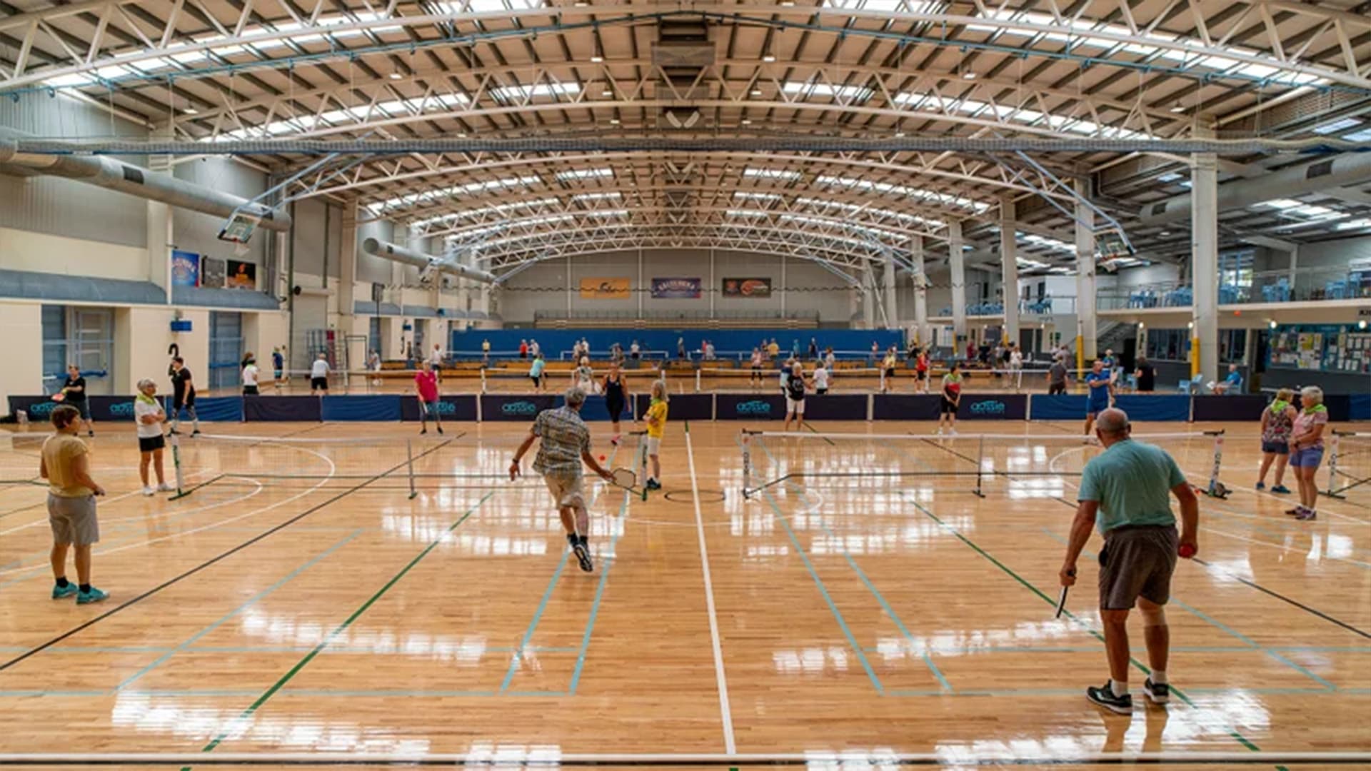 Multiple games of pickleball being played at the Caloundra Indoor Stadium with players spread across the whole court.