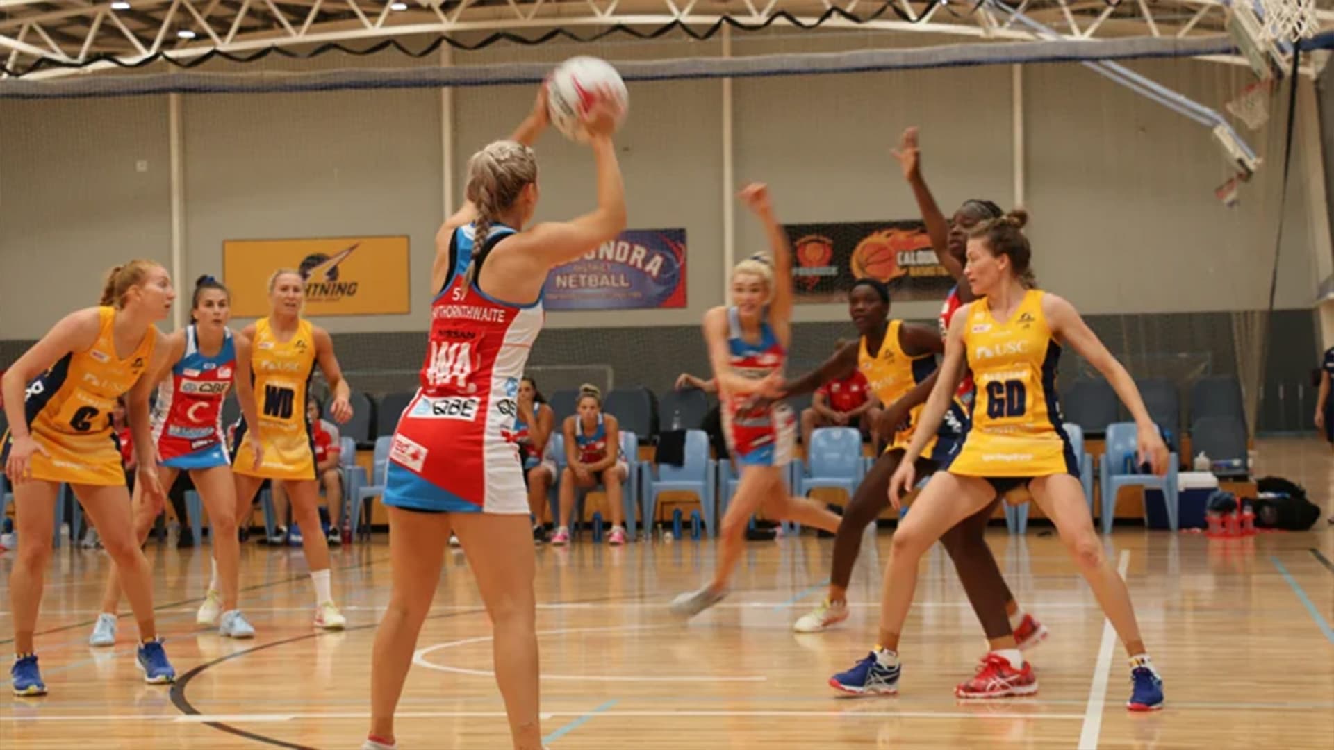 Netball players playing at the Caloundra Indoor Stadium with players spread across the court.