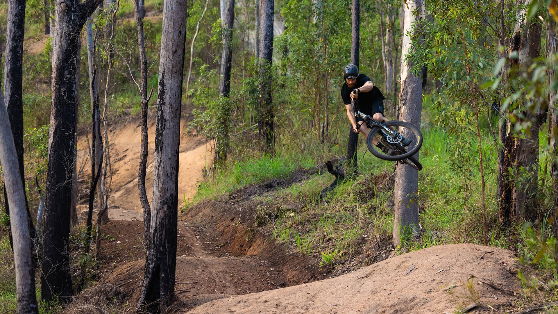 A mountain biker performing a jump on the dirt track at Finch Hatton MTB.