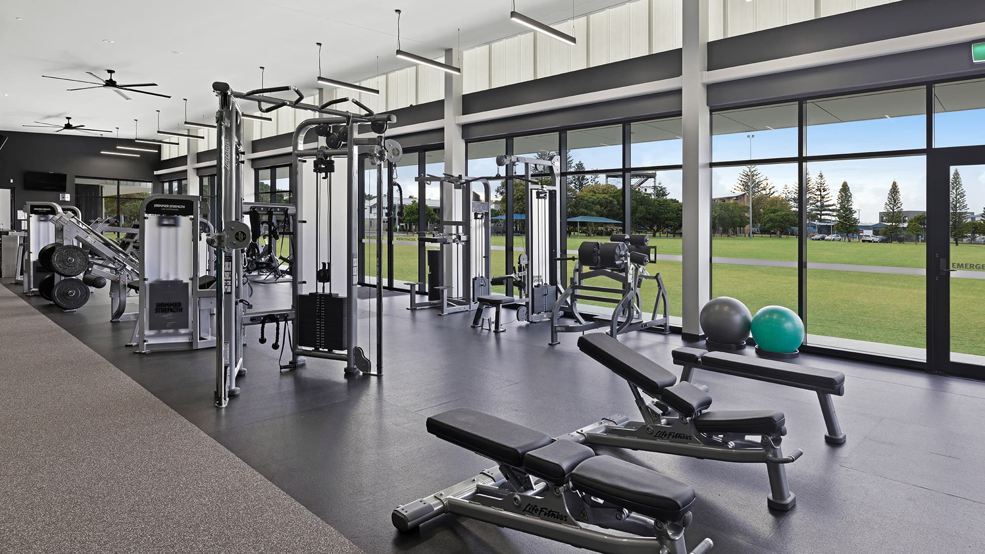 A wide angle view of an inside gym with a large window overlooking the grasslands. 