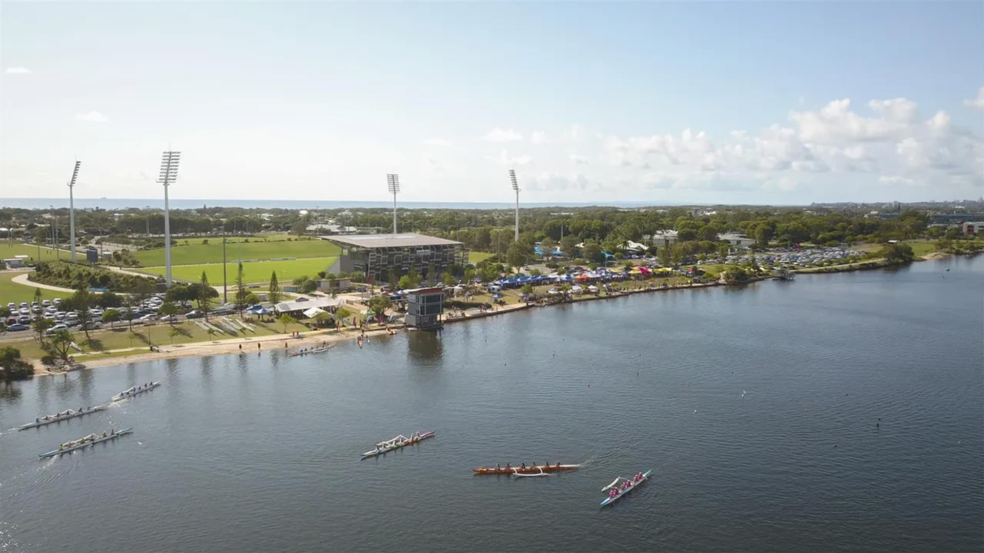 An aerial view of Lake Kawana with seven rowing boats on the water.