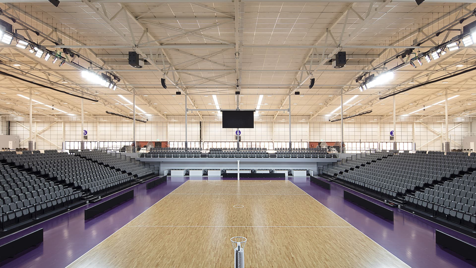 A wide angle view of the indoor Nissan Arena Netball court with empty stands and no players on the court. 