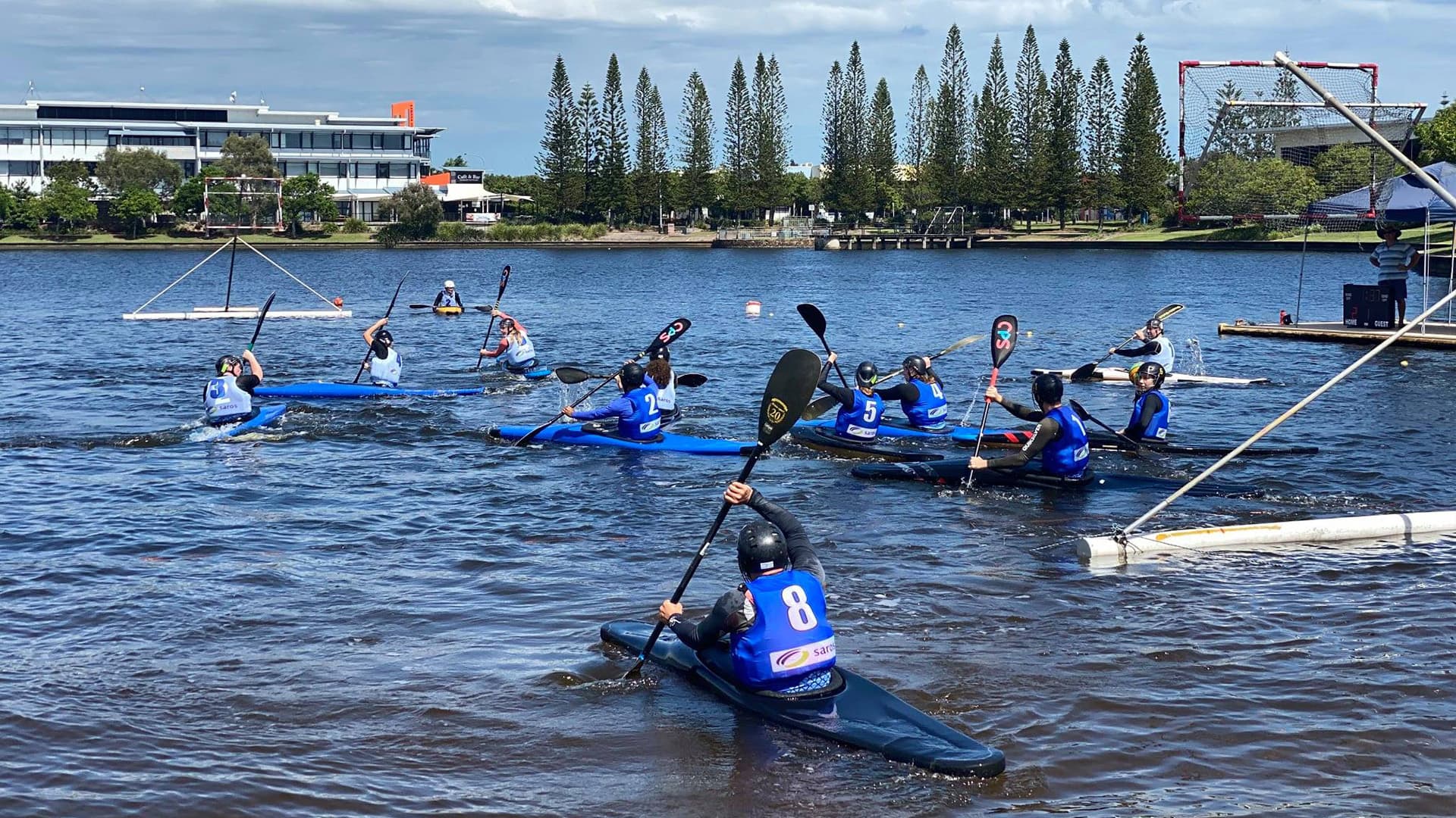 Two teams on the lake in canoes competing in a team sport.