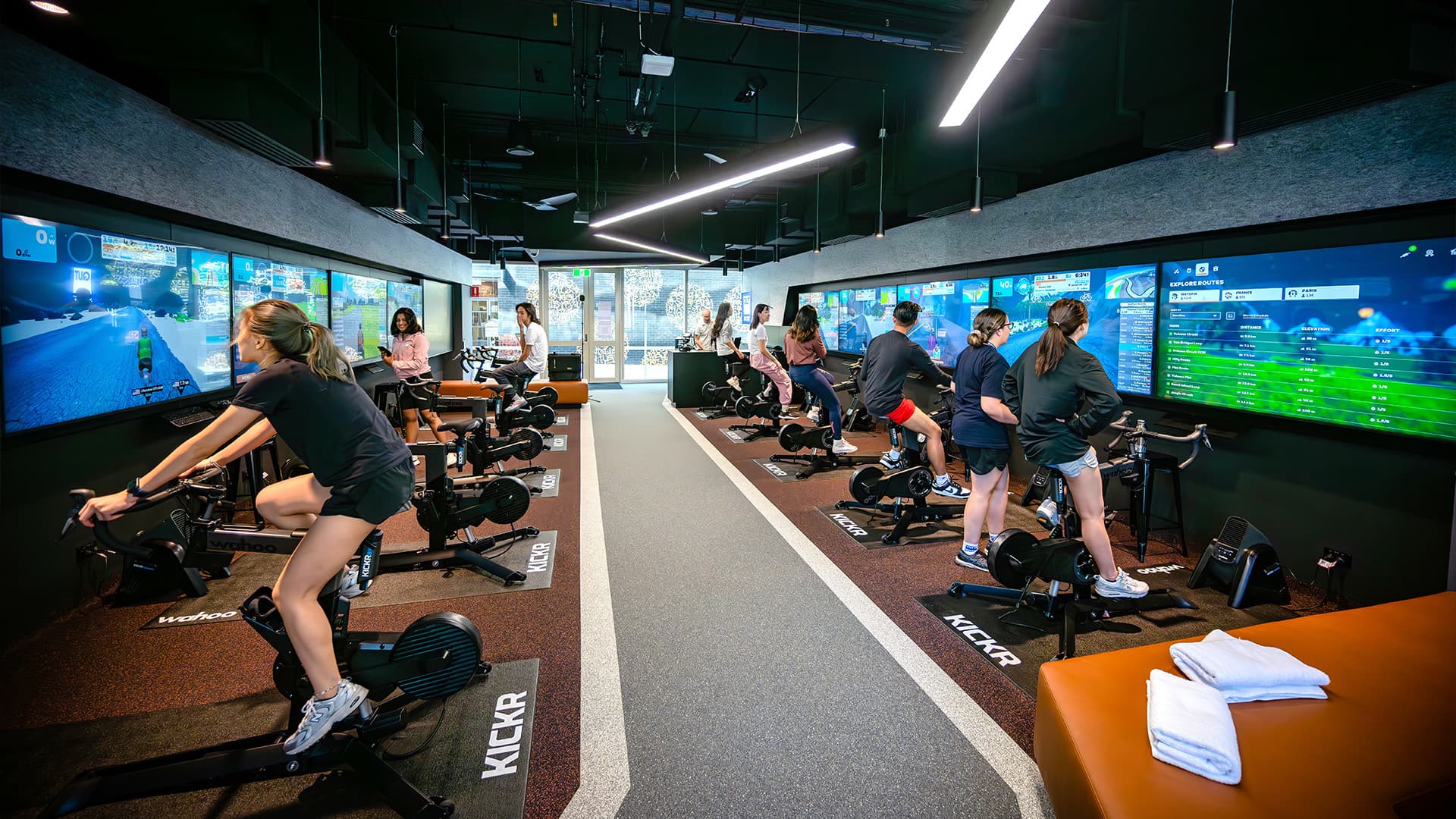 Students interacting with virtual exercise equipment connected to TV screens on the QUT Gardens Point Campus.