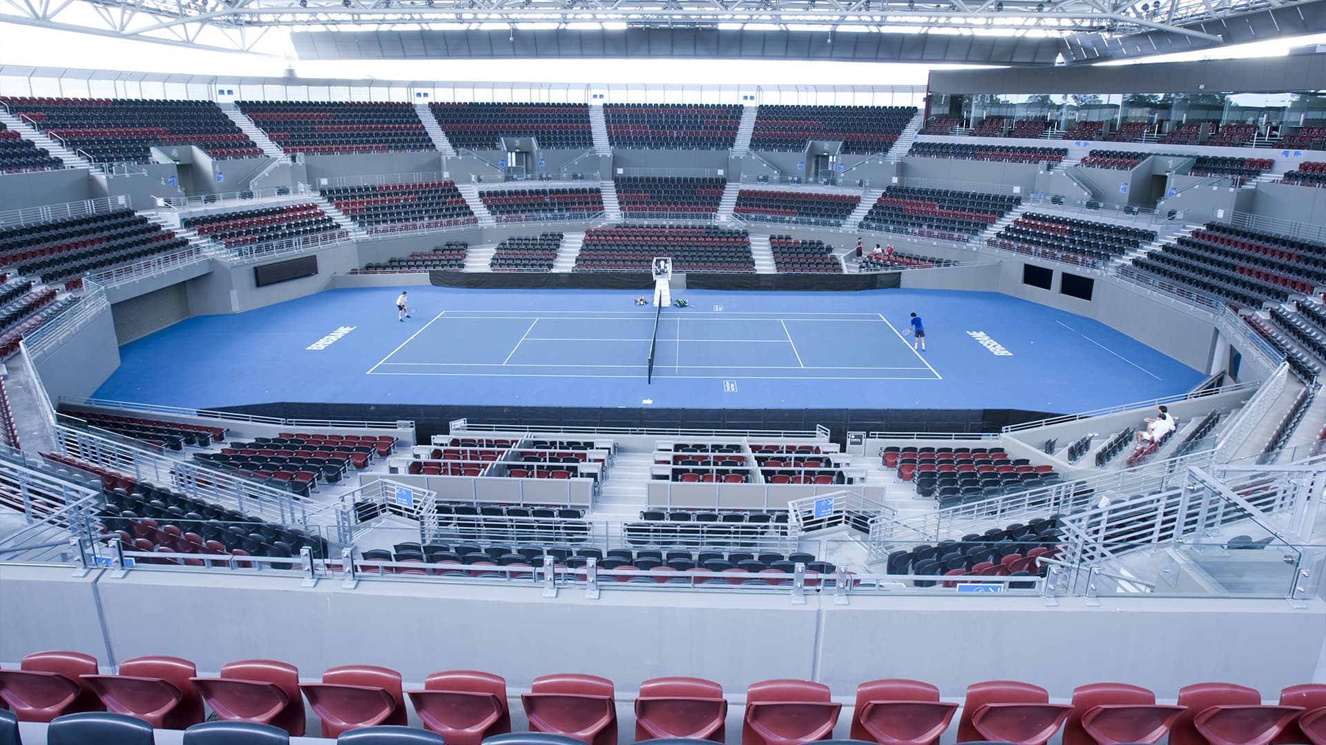 A wide angle view of the main tennis court at the Queensland Tennis Centre with empty stands and no players on the court.