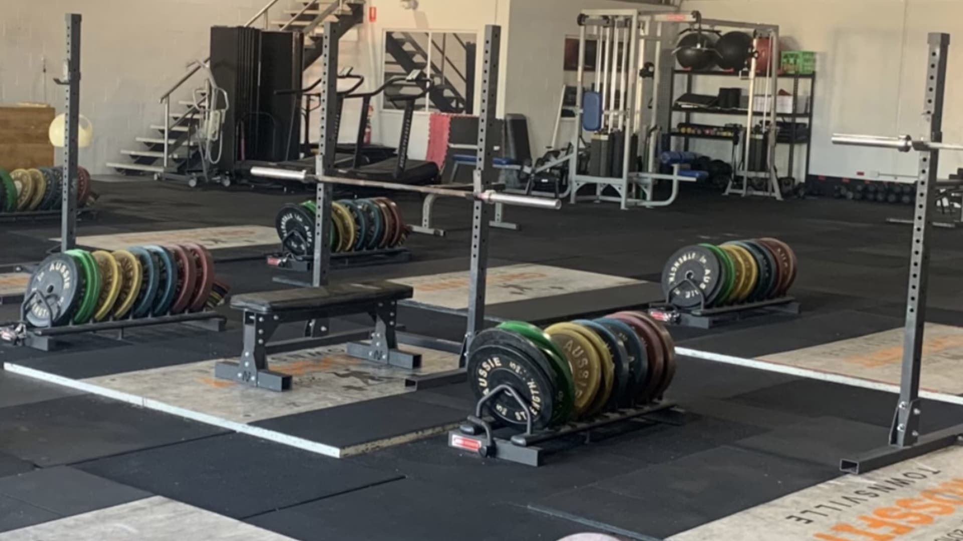 Close view of a bench press with colourful weights stacked next to it within the Thunder Barball weightlifting club.