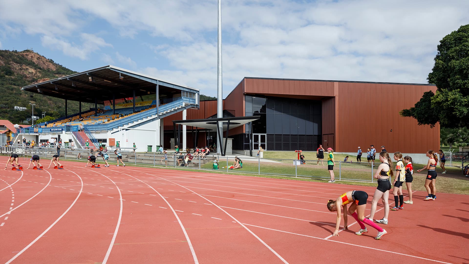 Two rows of young athletes lining up at the starting line, preparing for a race around the Townsville Sports Precinct track.